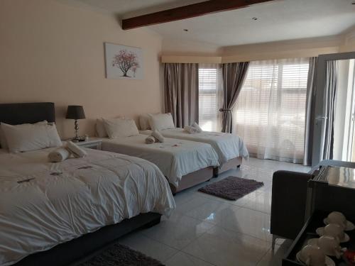 a hotel room with two beds and a window at Esperanca Guesthouse in Windhoek