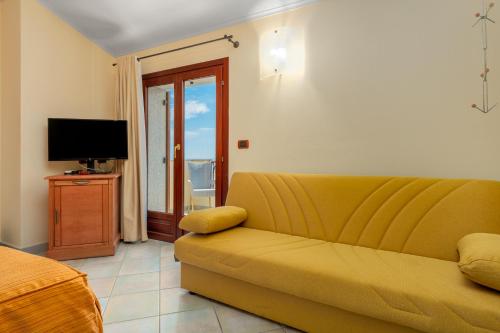 sala de estar con sofá amarillo y TV en Il Nuovo Gabbiano, en Cala Gonone