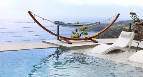 a hammock and chairs next to a swimming pool at Anemos Luxury Villas in Rodakino