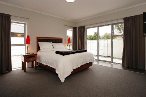 a bedroom with a large bed and windows at City Corporate Motor Inn in Palmerston North