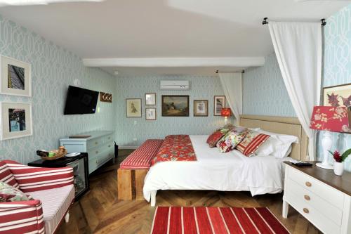 a bedroom with a large white bed and a couch at TW Guaimbê Exclusive Suítes in Ilhabela