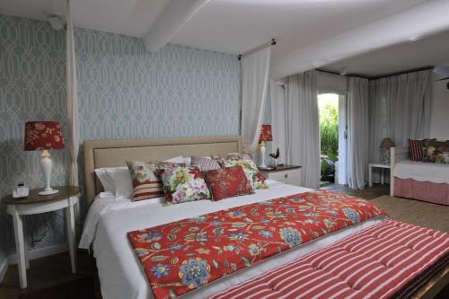 a bedroom with a large bed with a red blanket at TW Guaimbê Exclusive Suítes in Ilhabela