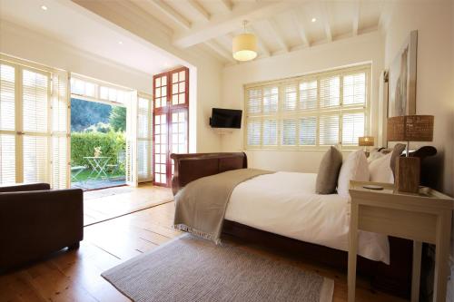 Schlafzimmer mit einem Bett, einem TV und Fenstern in der Unterkunft Daisybank Cottage Boutique Bed and Breakfast in Brockenhurst
