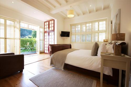 a bedroom with a bed and a television and windows at Daisybank Cottage Boutique Bed and Breakfast in Brockenhurst