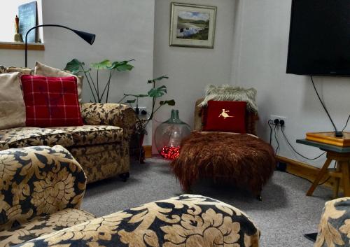 a living room with couches and a chair with a red pillow at Auld Skuil in Ashkirk