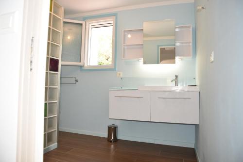 La salle de bains est pourvue de placards blancs et d'un lavabo. dans l'établissement Villa Fabregas, à La Seyne-sur-Mer