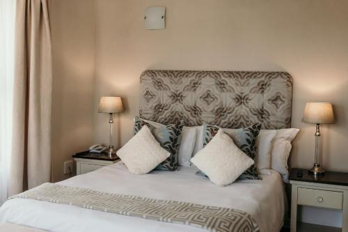 a bedroom with a bed with pillows and two lamps at Artemis Hotel Swakopmund in Swakopmund