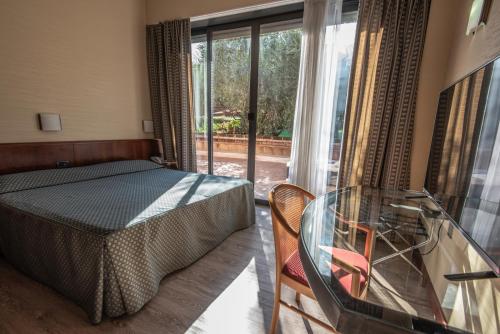 a bedroom with a bed and a glass table at Hotel Petra in La Romanina