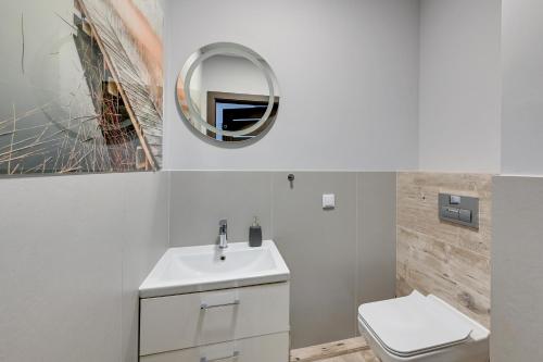 a bathroom with a sink and a toilet and a mirror at Grand Apartments - Luxury apartment on the 11th floor with a view of the Old Town in Gdańsk