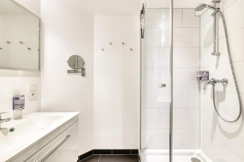 a white bathroom with a shower and a sink at Ferienwohnung Zentral mit Panorama-Sonnenterrasse by A-Appartments in Brand