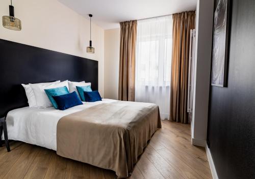 Habitación de hotel con cama grande con almohadas azules en Si Centrum Lipowa, en Białystok
