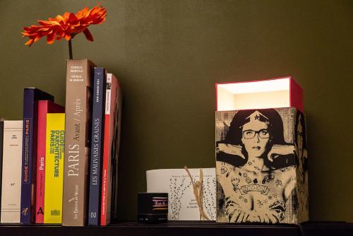 un estante con libros y un jarrón con una flor en Chambre d'hôtes de charme à Montreuil-Paris, en Montreuil