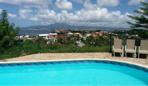 a pool with chairs and a view of a city at akate in Les Trois-Îlets