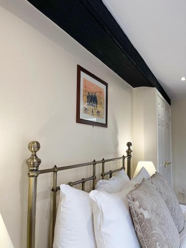 a bed with white pillows and a picture on the wall at Anglers Arms in Alnwick