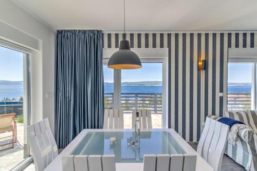 a dining room with a table and chairs with a view of the ocean at Villa Belissima Vista Mare in Selce
