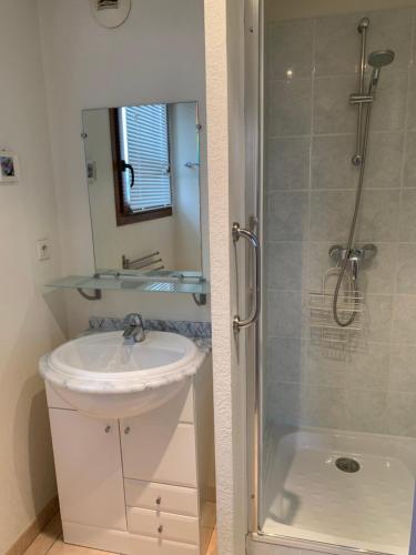 y baño blanco con lavabo y ducha. en Appartement dans résidence avec piscine et parking en Uzès