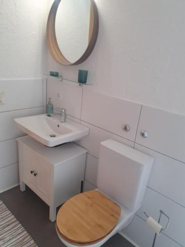 La salle de bains est pourvue de toilettes, d'un lavabo et d'un miroir. dans l'établissement Ferienwohnung mit Ausblick, à Kreuzlingen
