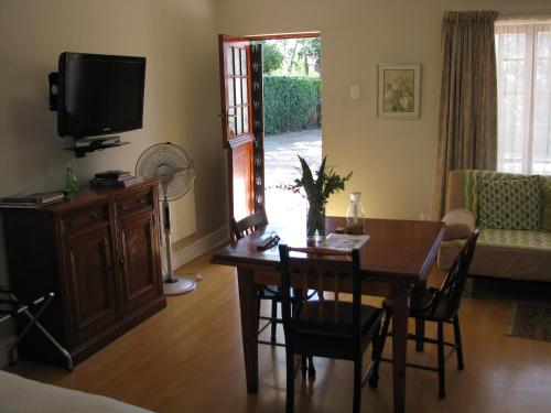 a living room with a dining room table and a tv at Kaiser's B&B in Grahamstown