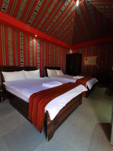 two beds in a room with red walls at Bidiya Desert Camp in Aflāj