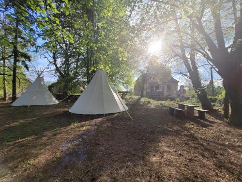 two tents in a field with a bench and a house at Chateau Moravany - apartmány, teepee a wellness in Ronow an der Doubrava
