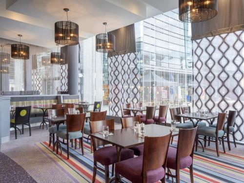 un restaurante con mesas, sillas y ventanas en Leonardo Hotel Leeds en Leeds