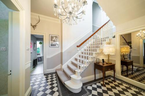 a hallway with a staircase and a chandelier at Villa by the Sea in Broughty Ferry