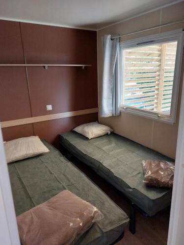 deux lits dans une chambre avec une fenêtre dans l'établissement mobil home tout confort 6 personnes climatisé au pied du Luberon, à La Roque-dʼAnthéron
