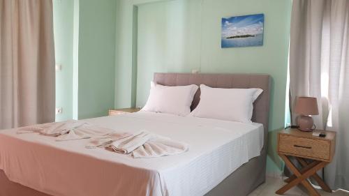 a bedroom with a white bed with two towels on it at Bayside Apartments in Vasiliki