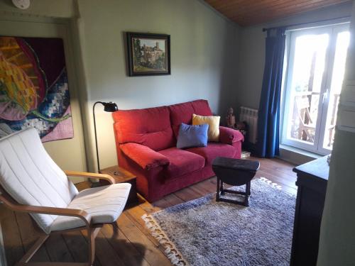 a living room with a red couch and a window at Casa de las Flores Sober Ribeira Sacra in Sober