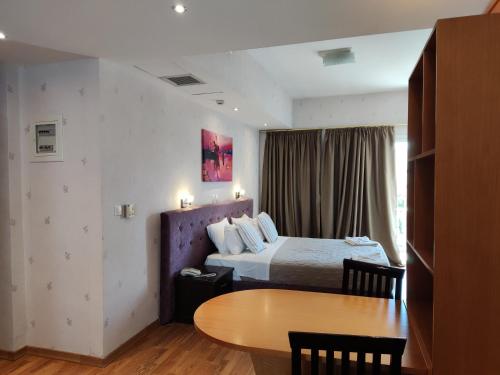 a hotel room with a bed and a table at Grand Olympic Hotel Loutraki in Loutraki