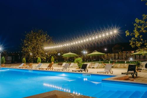 a pool with chairs and umbrellas at night at Hotel & Wine Cellar ARGE in Tʼelavi