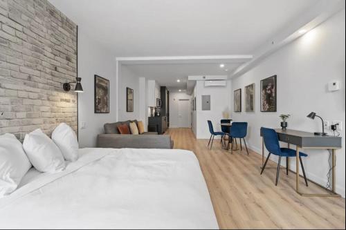 ケベック・シティーにあるINITIAL - ORIGINEL - Centre-Ville de Québecの白いベッドとレンガの壁が備わるベッドルーム1室が備わります。