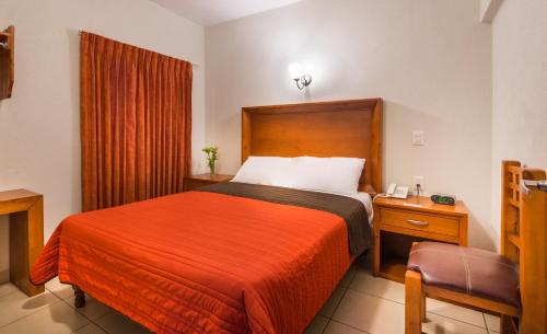a hotel room with a bed with a red blanket at Hotel Patzcuaro in Pátzcuaro