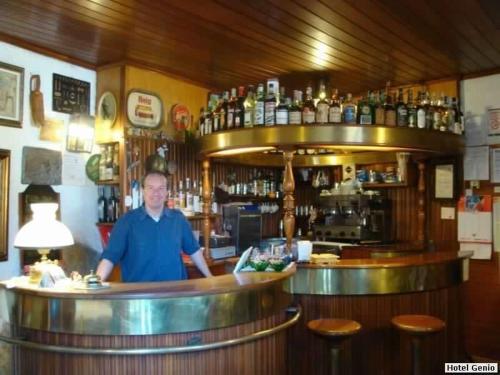 Un uomo in piedi dietro un bancone in un bar di Albergo Genio a Portovenere