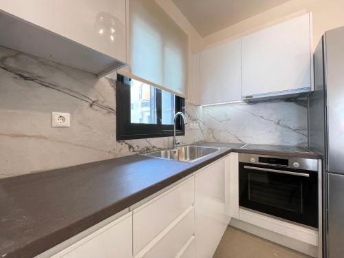 a kitchen with white cabinets and a stainless steel sink at Athenean Modern Escape near Marina Flisvos in Athens