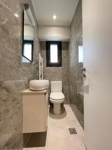 a bathroom with a white toilet and a sink at Athenean Modern Escape near Marina Flisvos in Athens