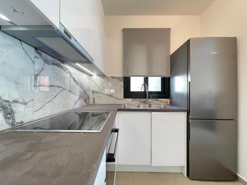 a kitchen with white cabinets and a stainless steel refrigerator at Athenean Modern Escape near Marina Flisvos in Athens