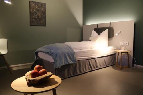 a bedroom with a bed with a bowl of apples on a table at Hotel Lindenhof Hubmersberg in Pommelsbrunn