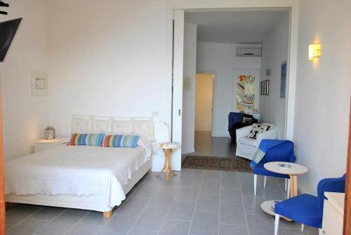 a bedroom with a white bed and blue chairs at Villa Arborea vista mare in Sperlonga