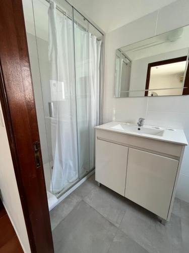 La salle de bains est pourvue d'un lavabo blanc et d'une douche. dans l'établissement O Cantinho, à Benavente