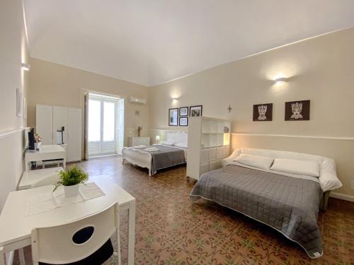 - une chambre avec 2 lits, un bureau et une table dans l'établissement Duomo Rooms b&b, à Lentini