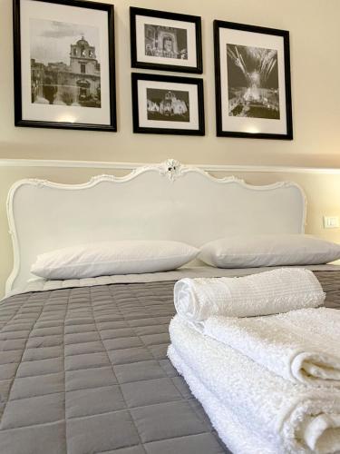 a bedroom with a white bed with pictures on the wall at Duomo Rooms b&b in Lentini