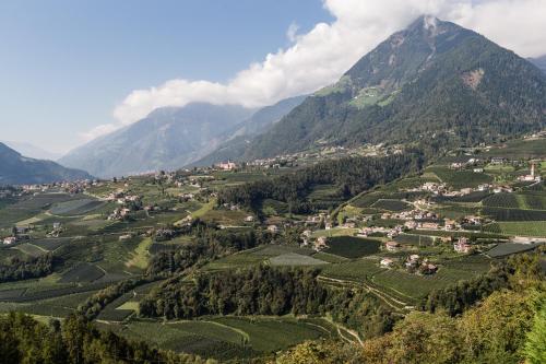 a village in a valley in the mountains at Hotel Finkennest - Panoramic Garden Resort in Schenna