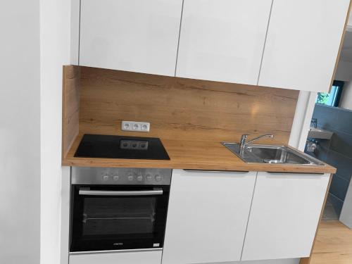 a kitchen with white cabinets and a stove and a sink at Traum Panorama Apartment mit Berg & Seeblick in Altmünster