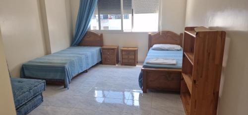 um pequeno quarto com 2 camas e uma janela em Appartement quiet sympa Rabat em Rabat