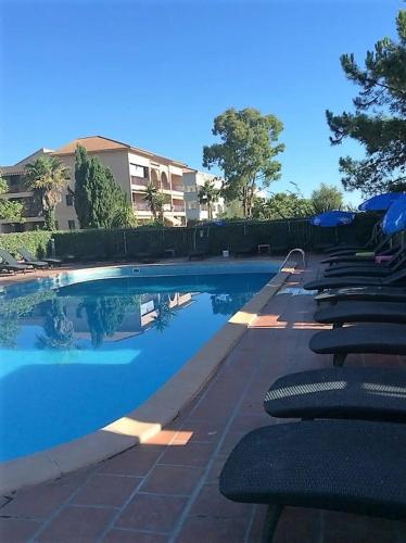 une piscine avec des chaises longues à côté d'un bâtiment dans l'établissement Résidence Les Marines de Moriani pieds dans l'eau duplex avec terrasses vue mer, 4-8 pers, à San-Nicolao
