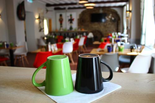 two green and black coffee mugs sitting on a table at Hotel Miriquidi All Inklusive in Kurort Oberwiesenthal