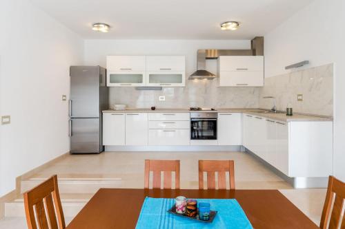 ミルナにあるBijaka Villas&apartmentsの白いキャビネット、テーブルと椅子付きのキッチンが備わります。