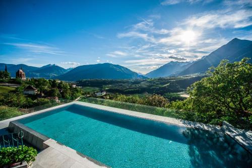 a swimming pool with mountains in the background at Hotel Finkennest - Panoramic Garden Resort in Schenna