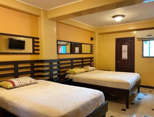 2 camas en una habitación con paredes amarillas en Hostal Montesa, en Guayaquil
